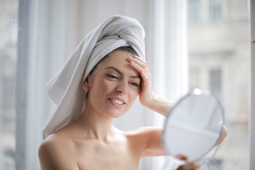 girl with towel on head looking at mirror